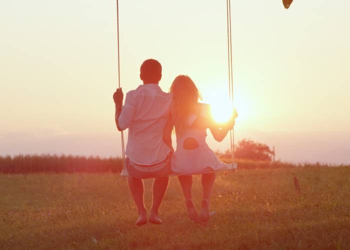 A guy and a girl sitting on a swing